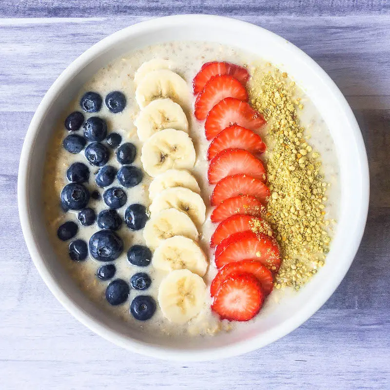 overnight oats in a bowl with strawberries, bananas, blueberries and bee pollen